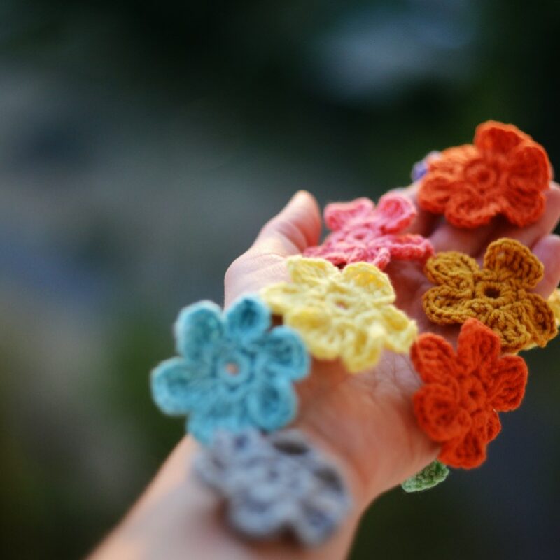 Crochet bag charms made with colorful yarn and handmade crochet flowers