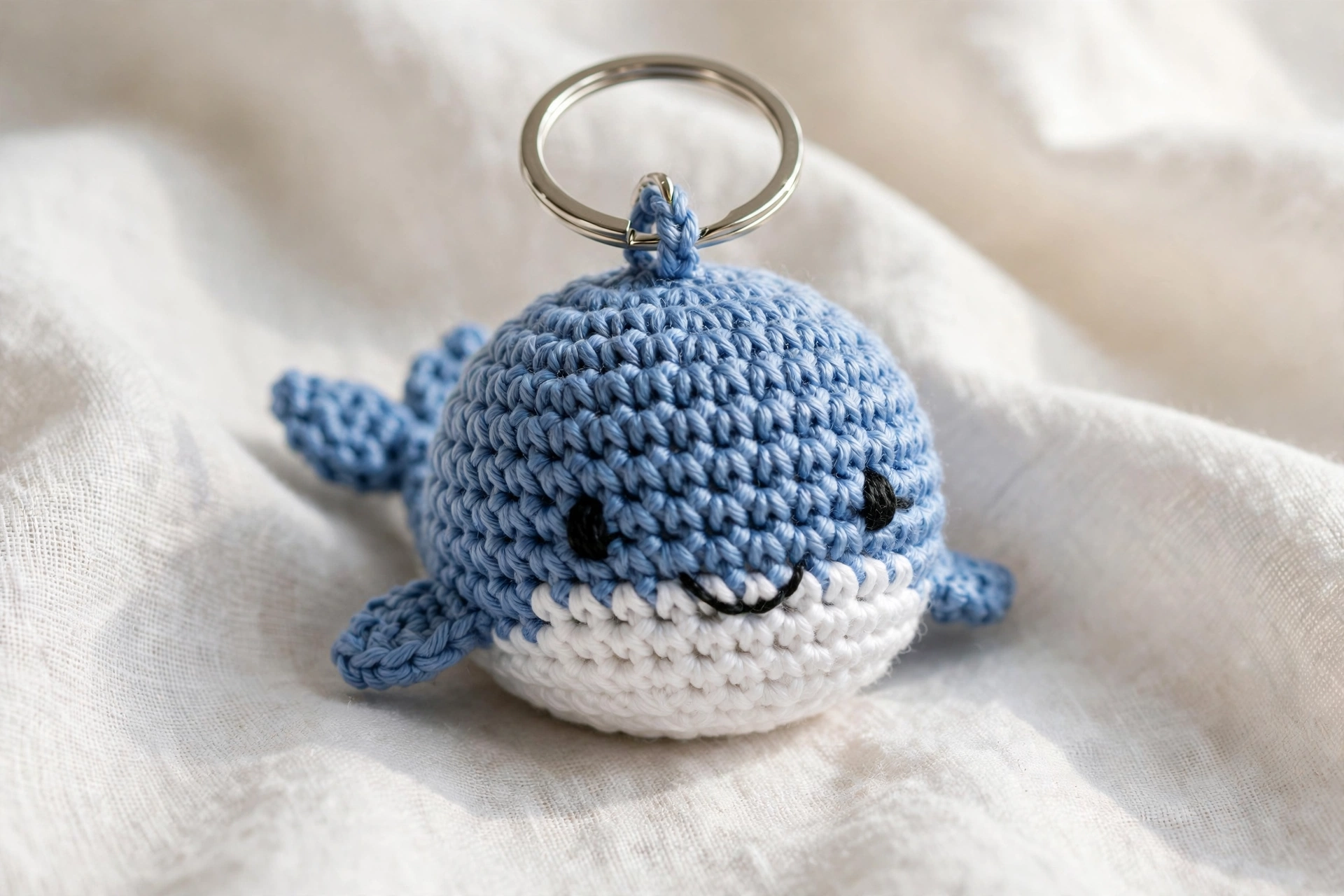 Close-up of a blue crochet whale keychain with a silver keyring